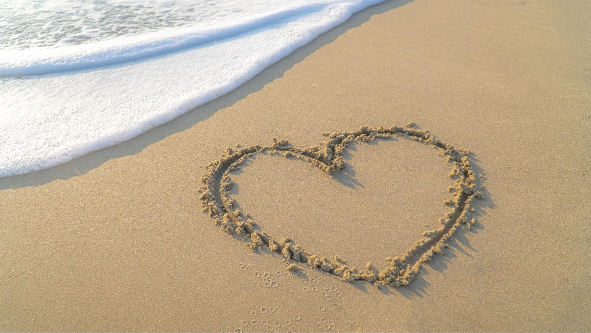 A heart-shaped drawing in the sand on the beach