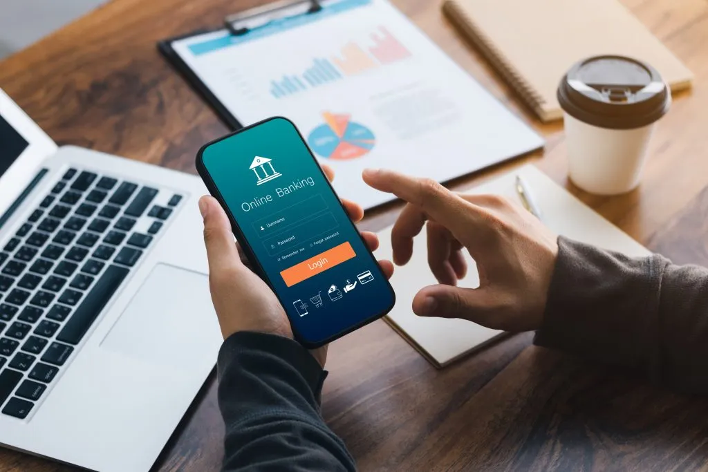 Person holding a phone and navigating through a mobile banking app.