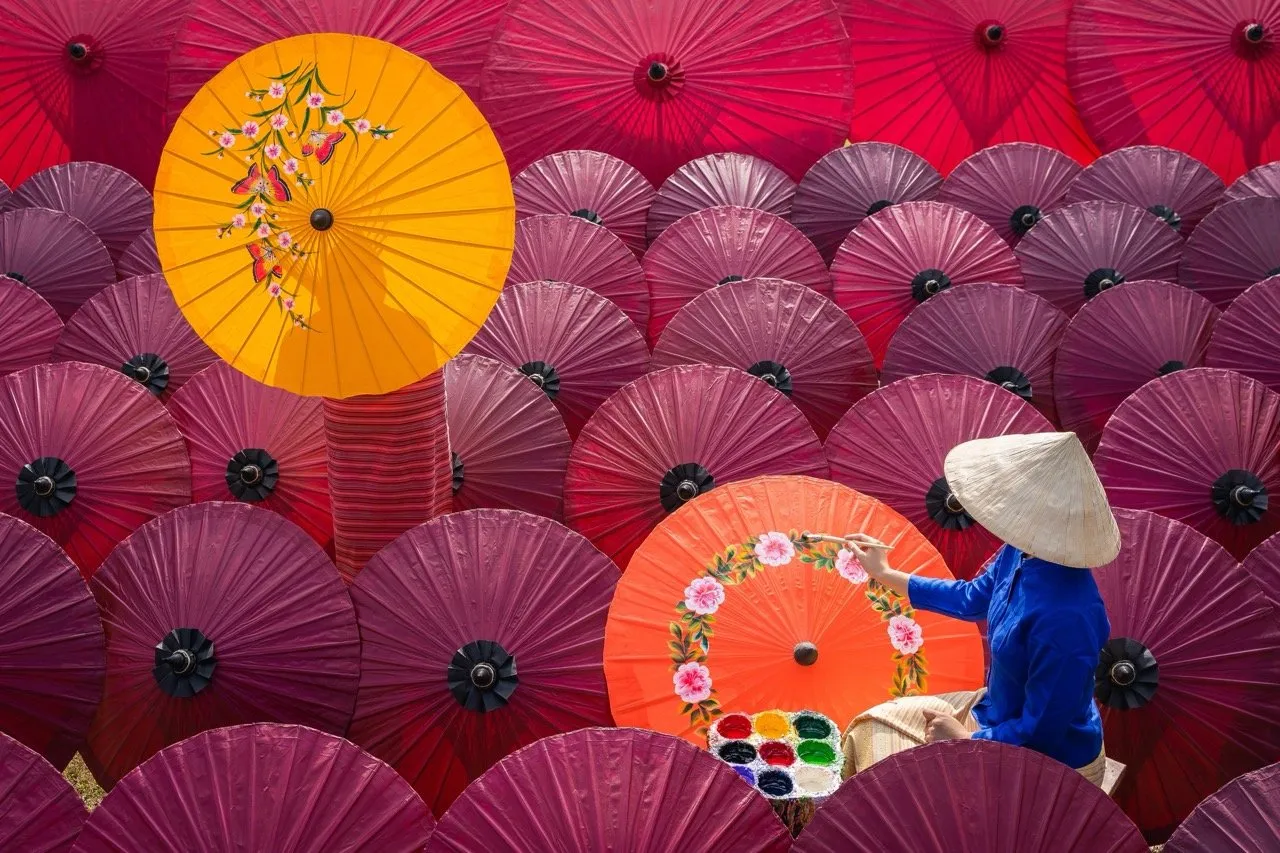 Women painting beautiful handmade paper umbrellas in Chiang Mai Thailand