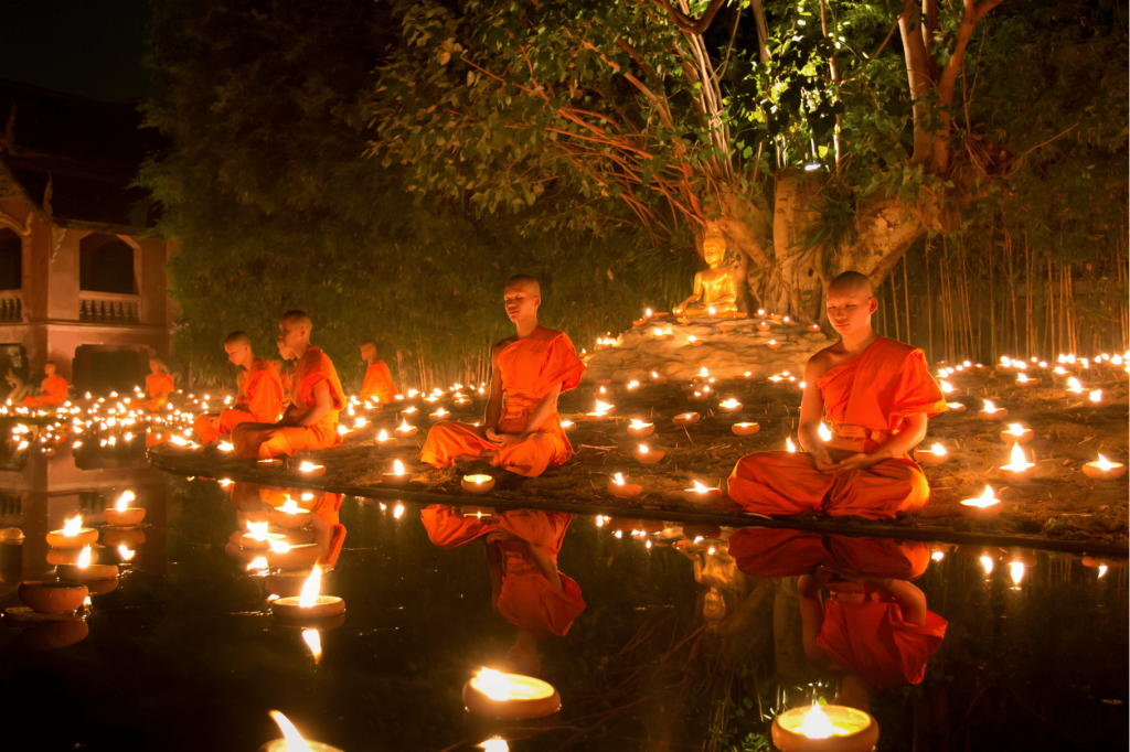 buddhist monks praying in candlelight during vassa or khao phansa