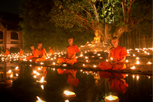 buddhist monks praying in candlelight during vassa or khao phansa