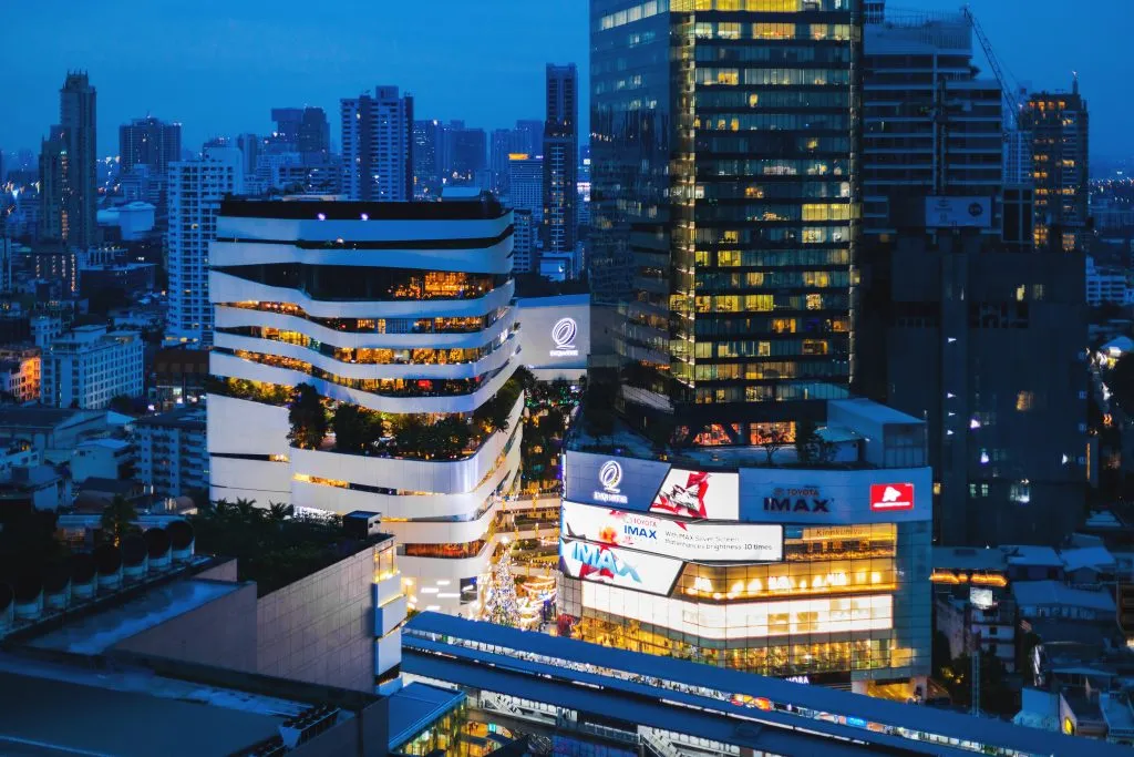 Night shot of The Emquartier Shopping Mall with the view of Bangkok Skyline on Sukhumvit road.