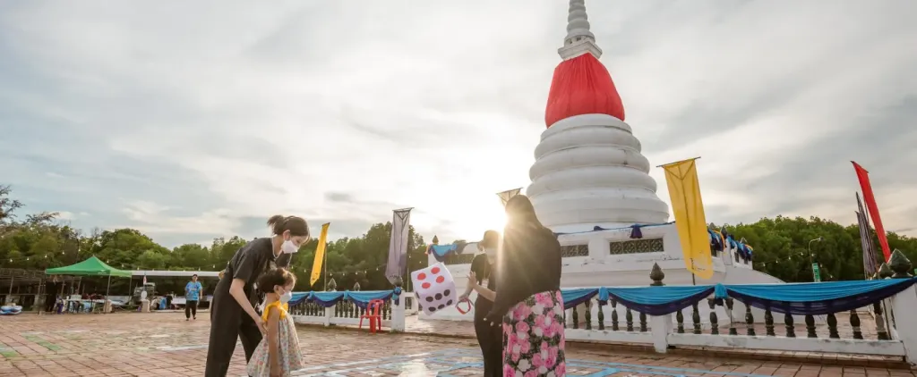 mother and her child standing in front of a pagoda  what a portion of the top part being wrapped around by red clothe.