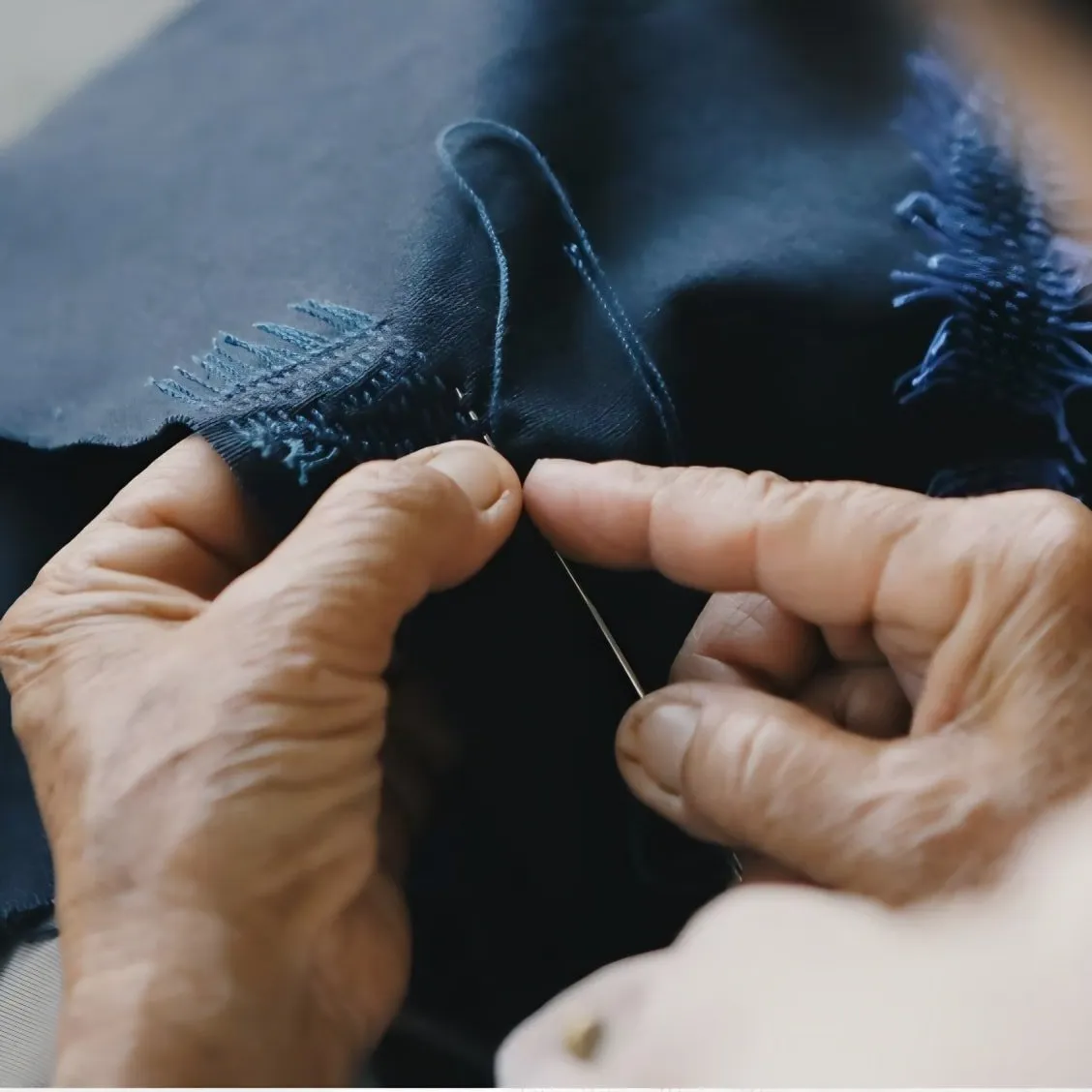 A Thai artisan sewing a pattern onto a piece of fabric