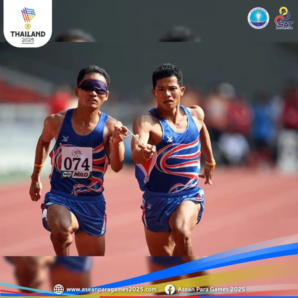 two runners dashing together, the left arm of the one on the left is tide to the one on the right. the left runner is blindfolded.