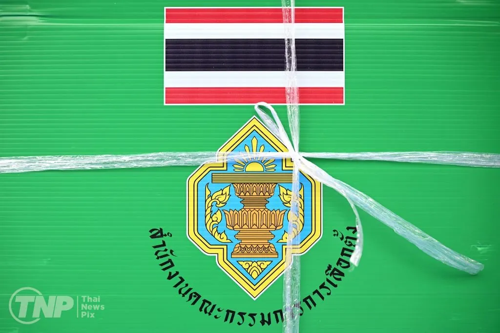 A green, corrugated ballot box is tightly secured with clear plastic straps. It features the Thai flag and the official seal of the Election Commission of Thailand.