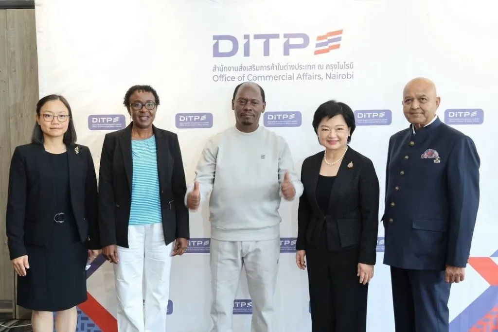 Five Thai and Kenyan delegates pose before a DITP Nairobi backdrop. A central man in grey offers a friendly double thumbs-up.
