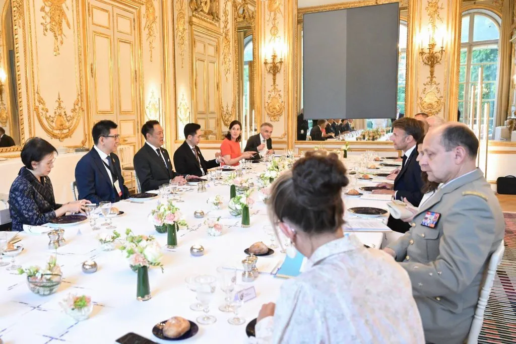 Delegation members sit along a long, formal dining table.