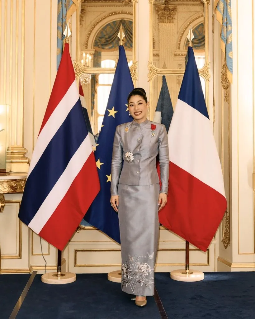 The princess smiles while standing in front of flags.