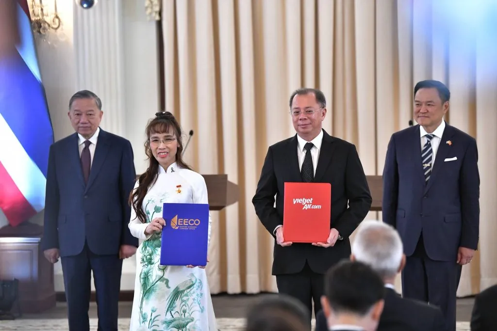 A woman and a man stand holding colored folders, with two men standing beside them.