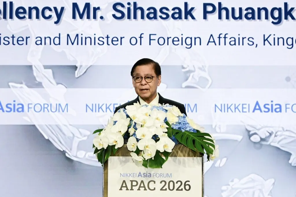 Deputy Prime Minister and Minister of Foreign Affairs Sihasak Phuangketkeow speaks at a floral-decorated podium.