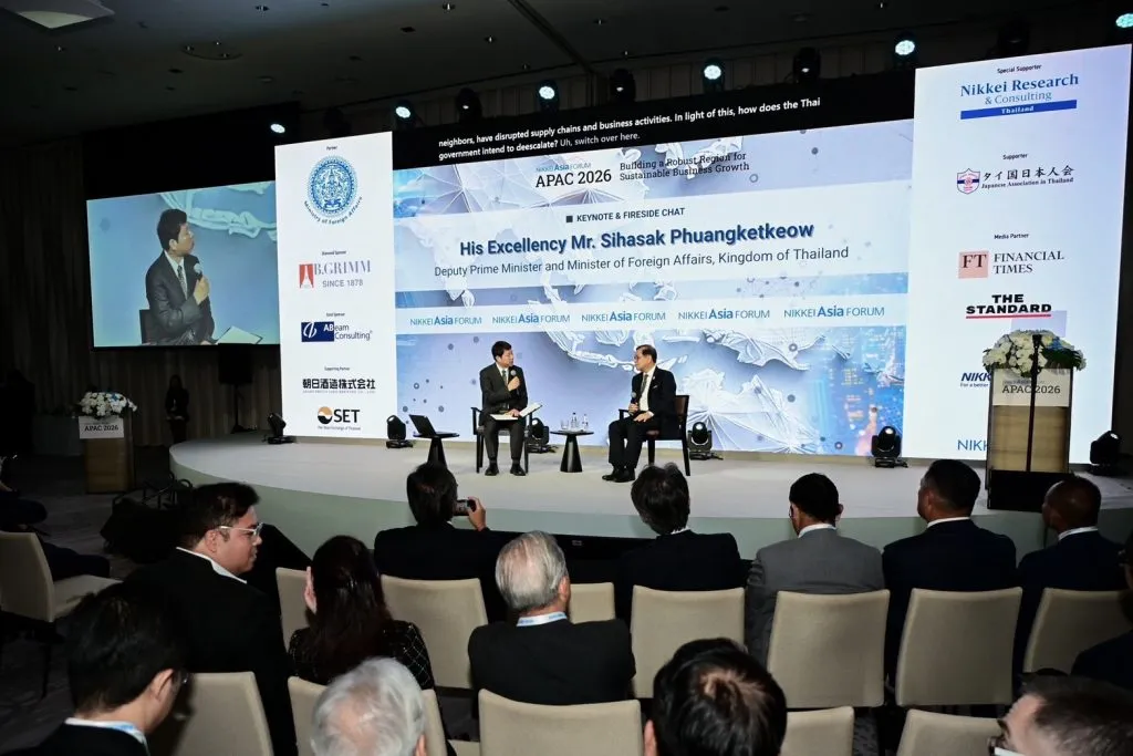 H.E. Mr. Sihasak Phuangketkeow participates in an on-stage fireside chat before a large seated audience.