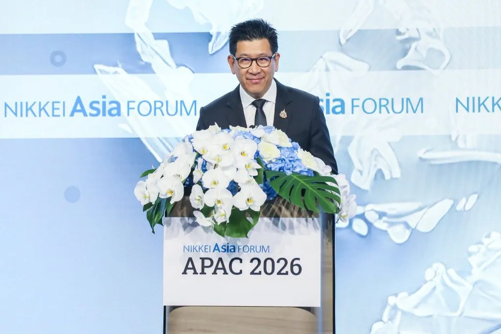 Deputy Prime Minister Ekniti Nitithanprapas standing behind the podium in front of a white/blue backdrop.