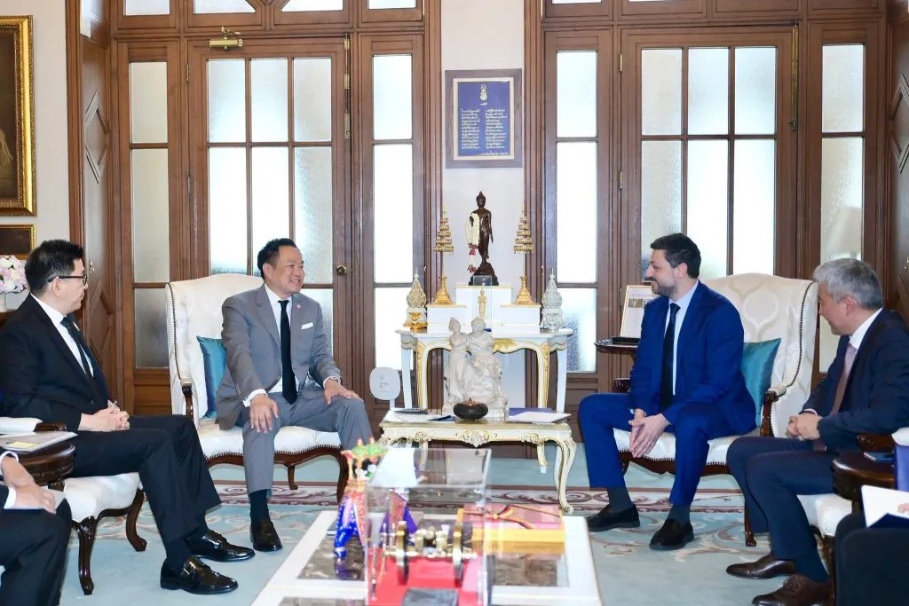 Prime Minister Anutin Charnvirakul and a foreign delegate converse while seated in an ornate reception room.