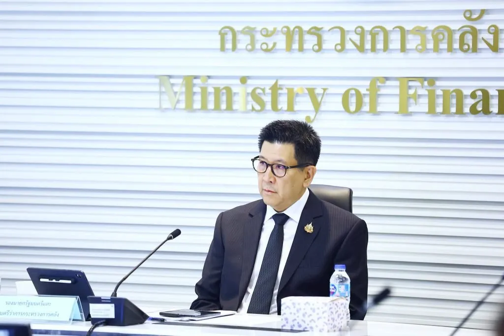 Deputy Prime Minister and Finance Minister Ekniti Nitithanprapas sits behind a conference table microphone.