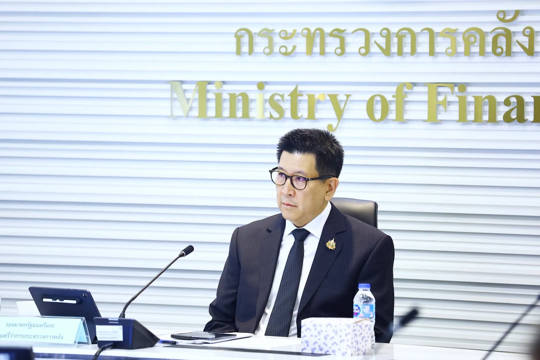 Deputy Prime Minister and Finance Minister Ekniti Nitithanprapas sits behind a conference table microphone.