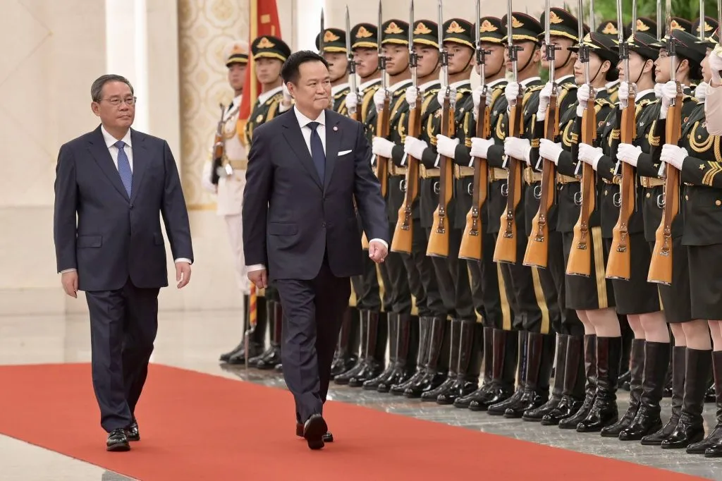 Chinese Premier Li Qiang and Thai Prime Minister Anutin Charnvirakul walk past an honor guard.
