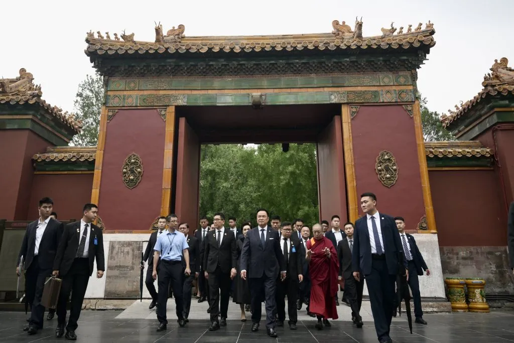 Prime Minister Anutin Charnvirakul and his delegation walk through an ornate traditional archway together.