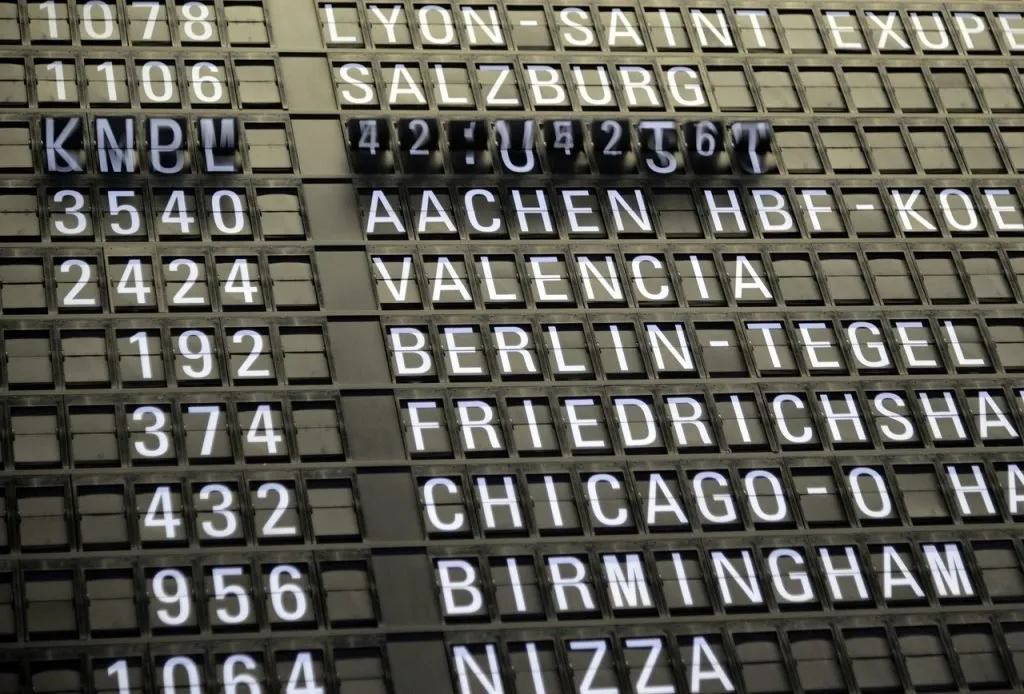 Airport bill board with various destinations on it.
