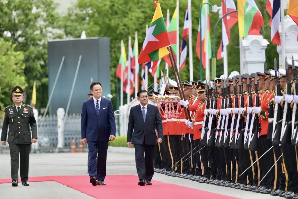 Anutin Charnvirakul and Min Aung Hlaing walk along a red carpet during an official military honor guard parade.