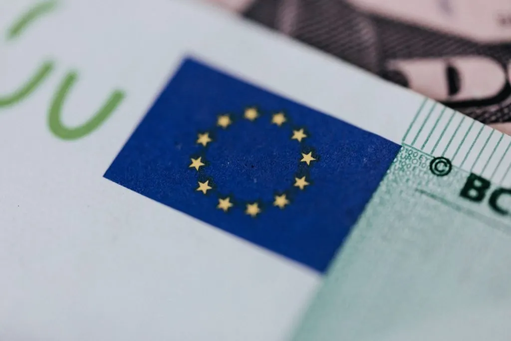Extreme close-up of a green Euro banknote displaying the blue European Union flag with yellow stars.