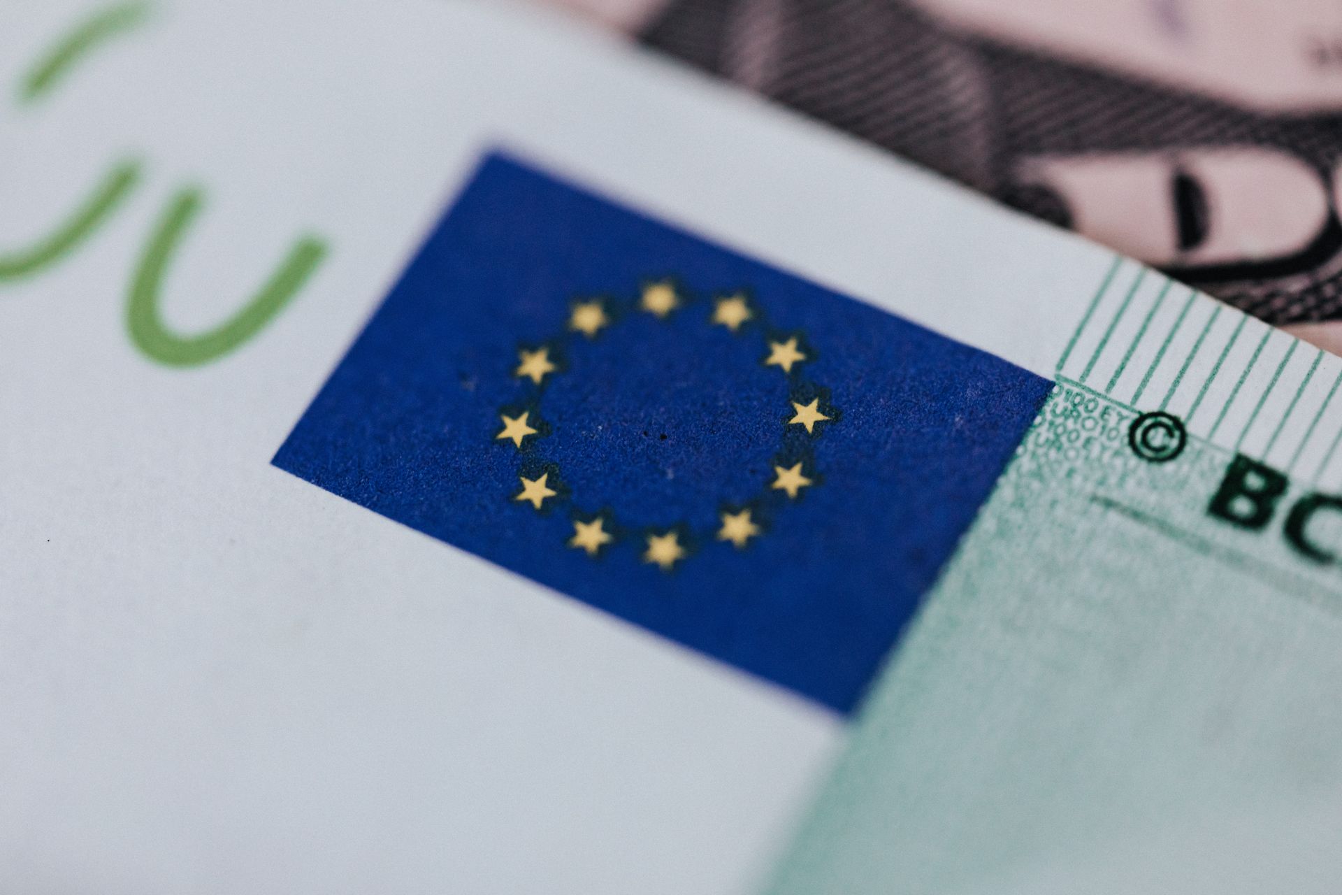 Extreme close-up of a green Euro banknote displaying the blue European Union flag with yellow stars.