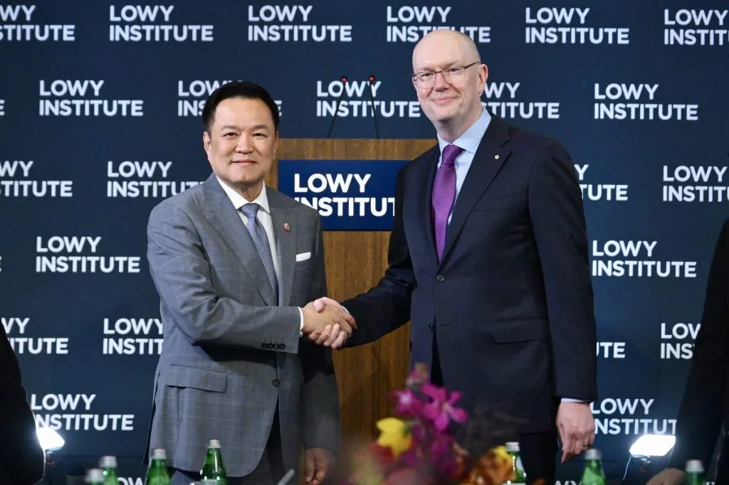 Thai prime minister shakes hands with Lowy Institute executive before a branded backdrop in Sydney.