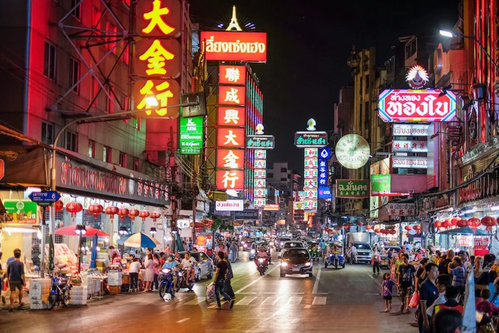 Yaowarat Road in Bangkok’s Chinatown illuminated by neon signs and street activity at night.