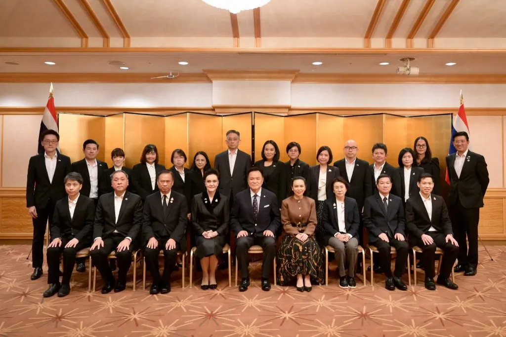 Prime Minister Anutin Charnvirakul sits with members of Team Thailand for a group photo in Tokyo.