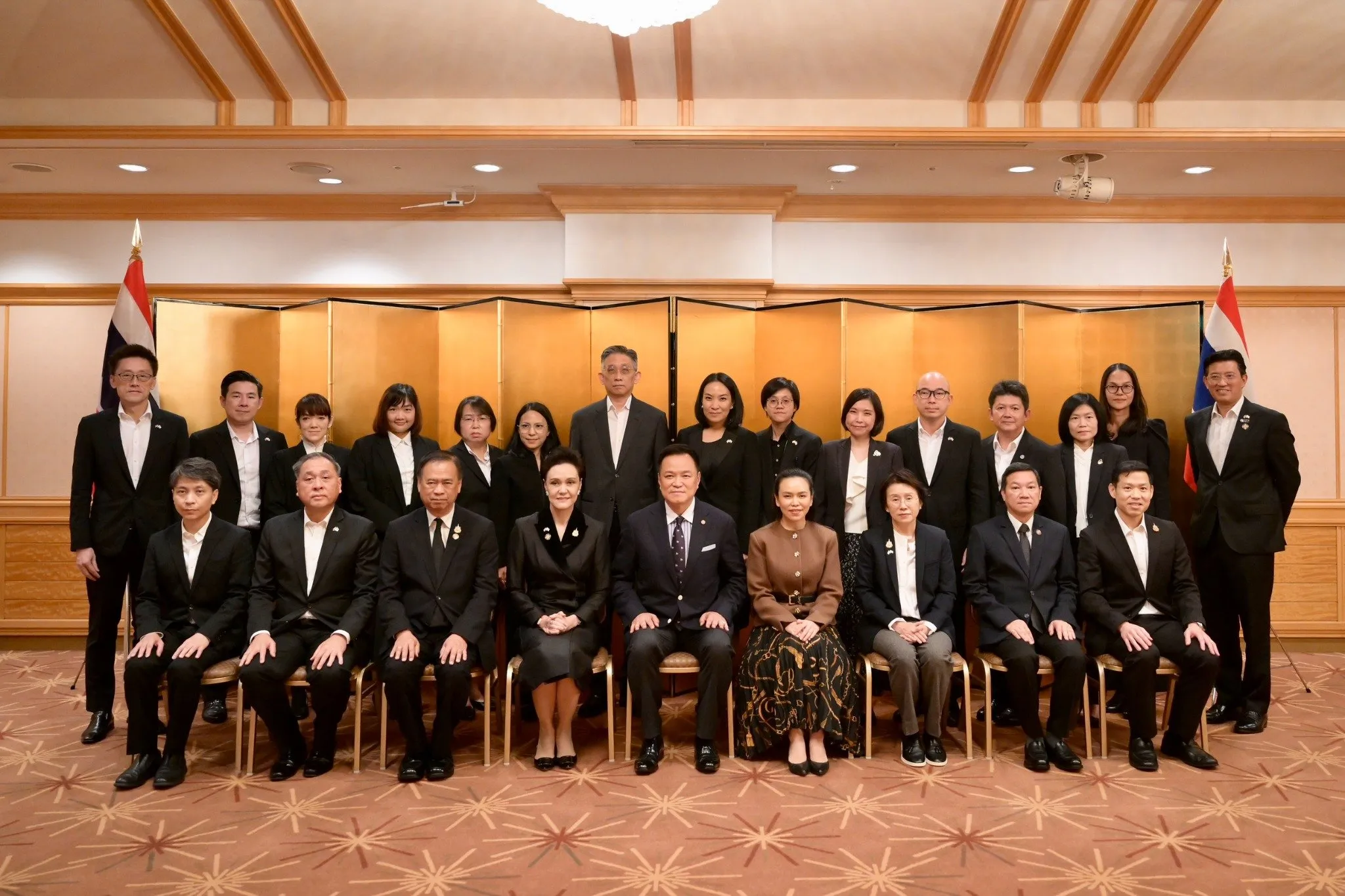 Prime Minister Anutin Charnvirakul sits with members of Team Thailand for a group photo in Tokyo.