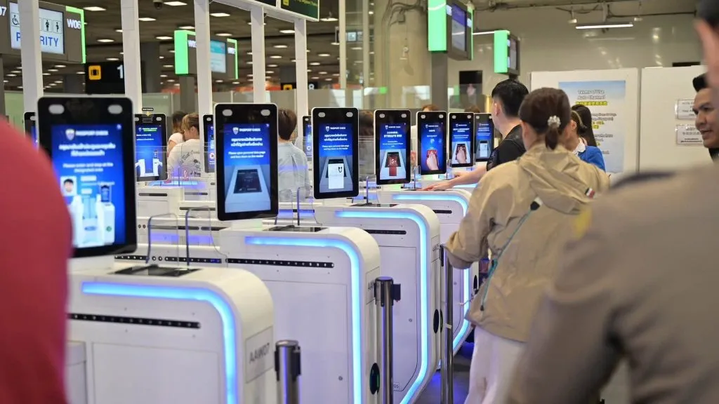 Passengers and officials beside automated passport-control gates at Suvarnabhumi Airport.