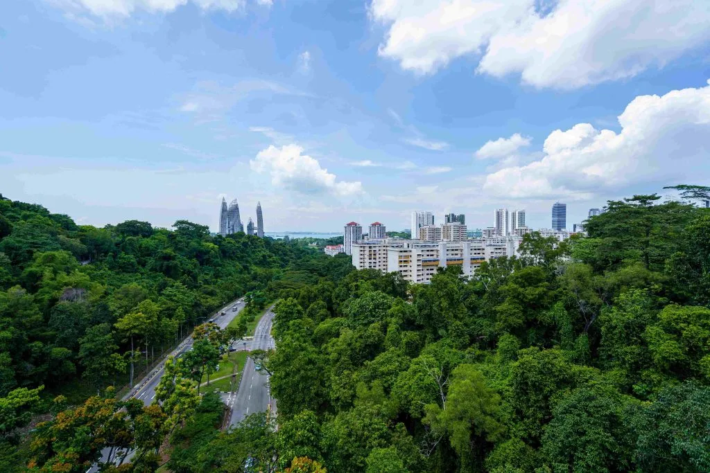Modern buildings stand beside trees and green open space.